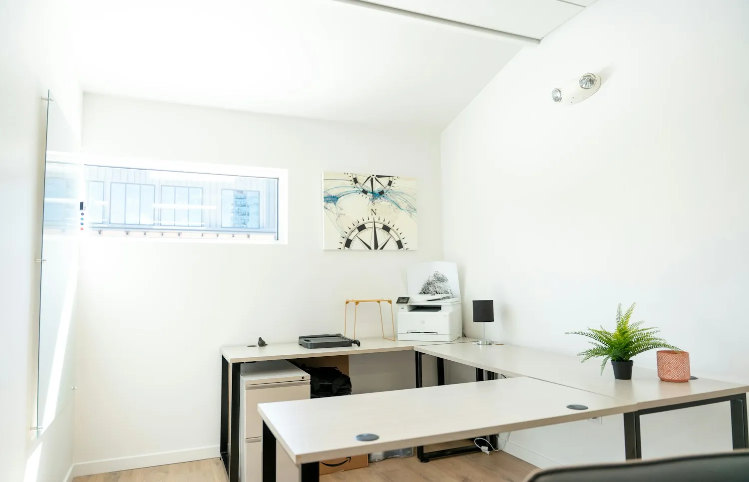 Illustrative office with light desks, a window and uncluttered work surfaces
